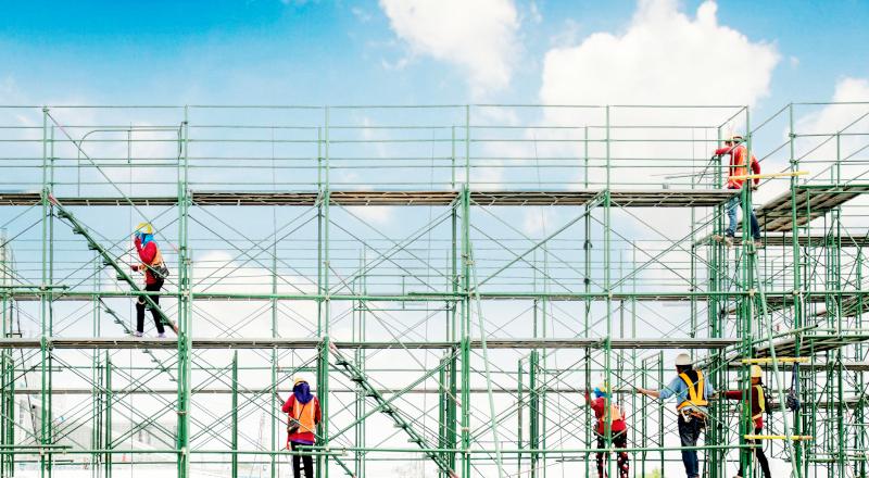 A group of construction workers on scaffolding in construction site. (1)