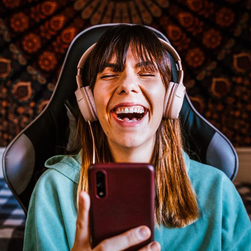 A young woman wearing headphones laughs