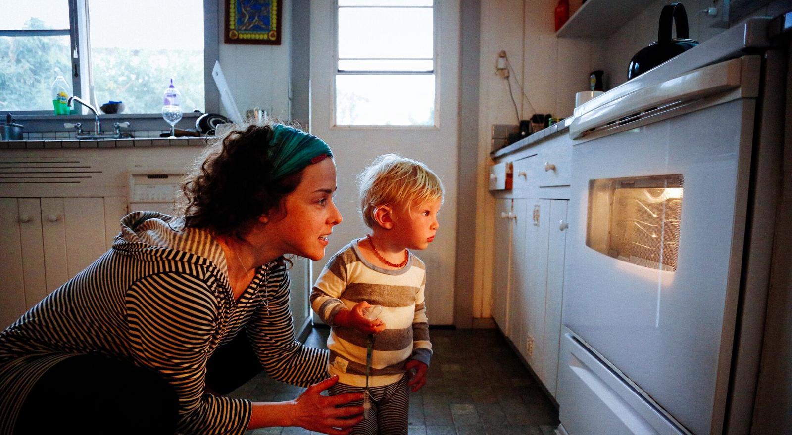 Large Web and Screen A woman and a young boy are watching food cook through the oven window in the kitchen Large Web and Screen A woman and a young boy are watching food cook through the oven window in the kitchen
