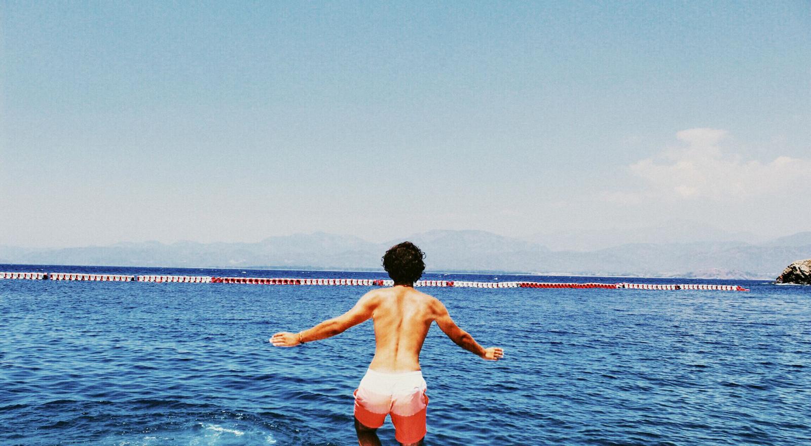 Large Web and Screen Back view of a man in swim shorts about to jump into the water Large Web and Screen Back view of a man in swim shorts about to jump into the water