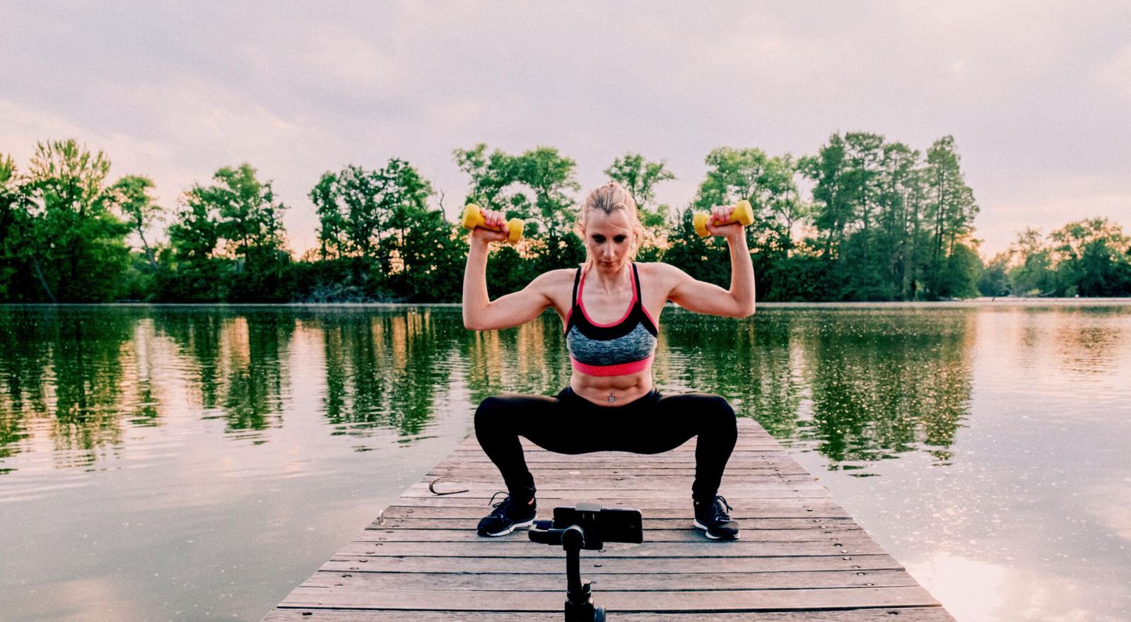 Large Web and Screen Fit female athlete working out and vlogging outdoor with a mobile phone