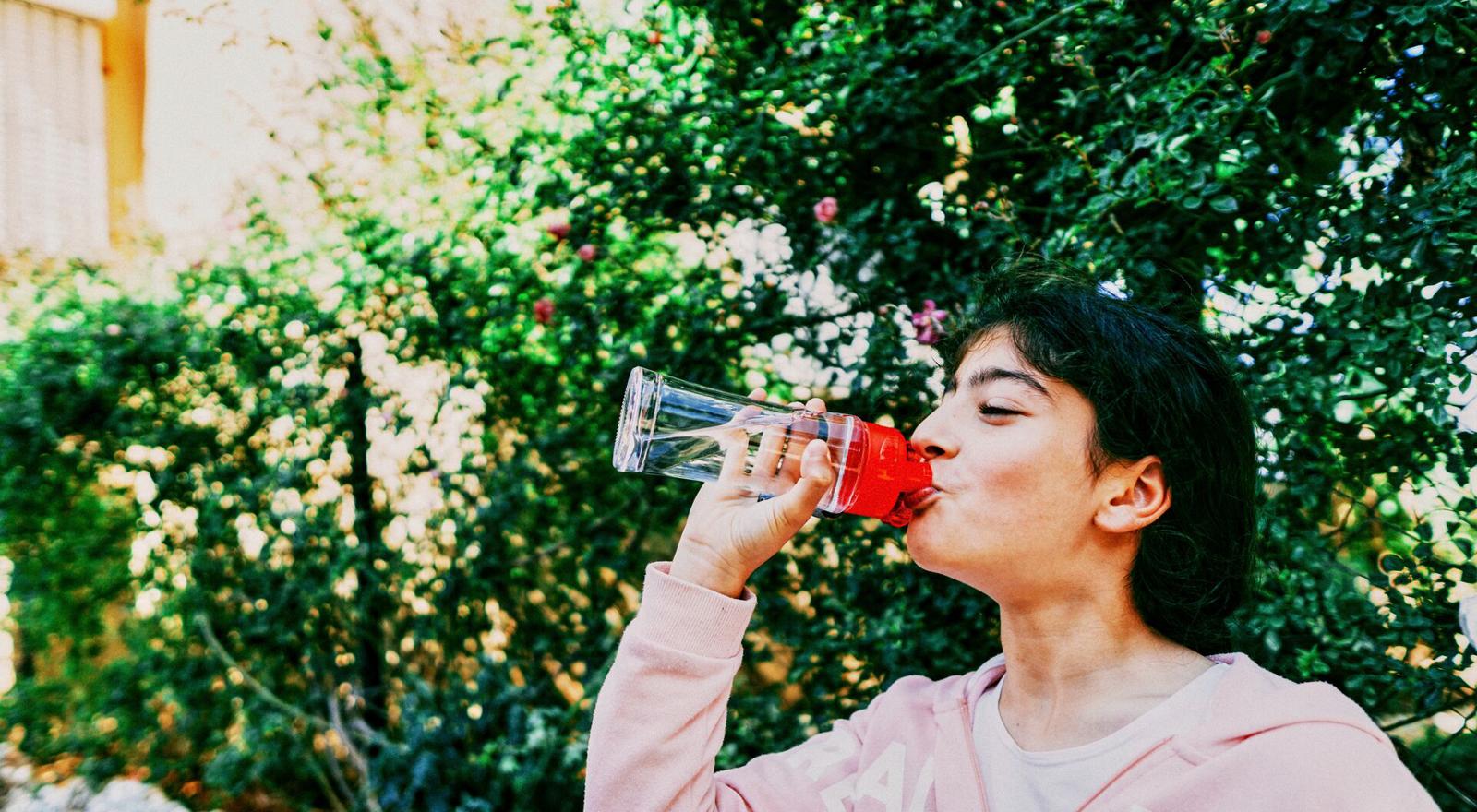 Large Web and Screen Young girl drinking a bottle of water outside