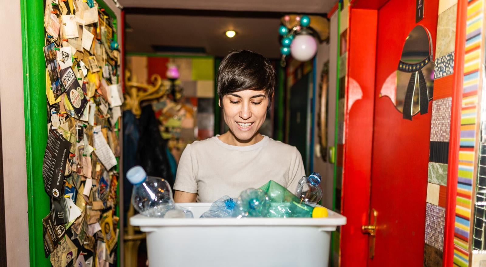 Large Web and Screen Young woman carrying a container of plastic bottles for recycling