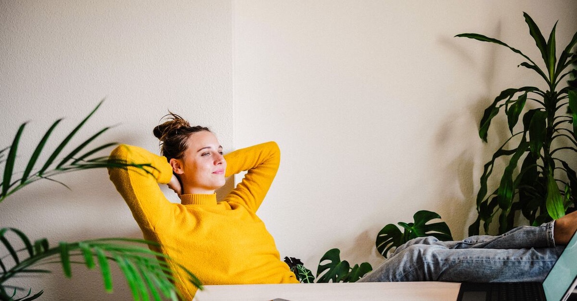 LinkedIn and Facebook Young woman in yellow sweater reclining at her desk (1)